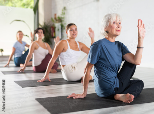 Active senior woman exercising stretching workout and incline during yoga class in modern fitness studio