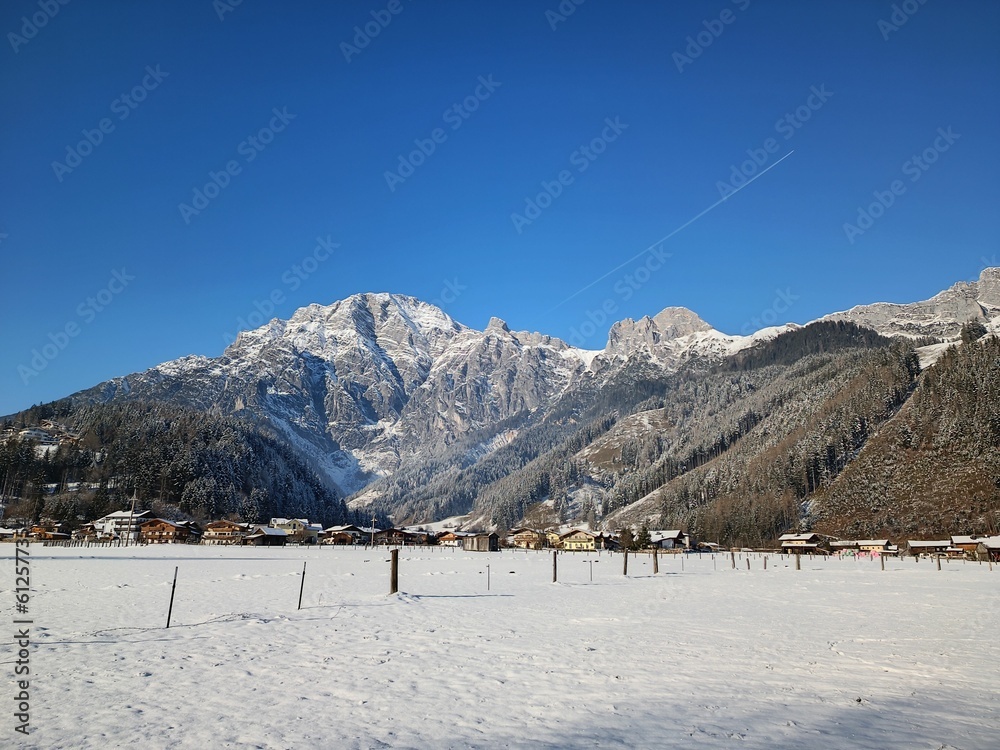 Vertical shot of rocky mountains with snowy peaks and a village on the slopes