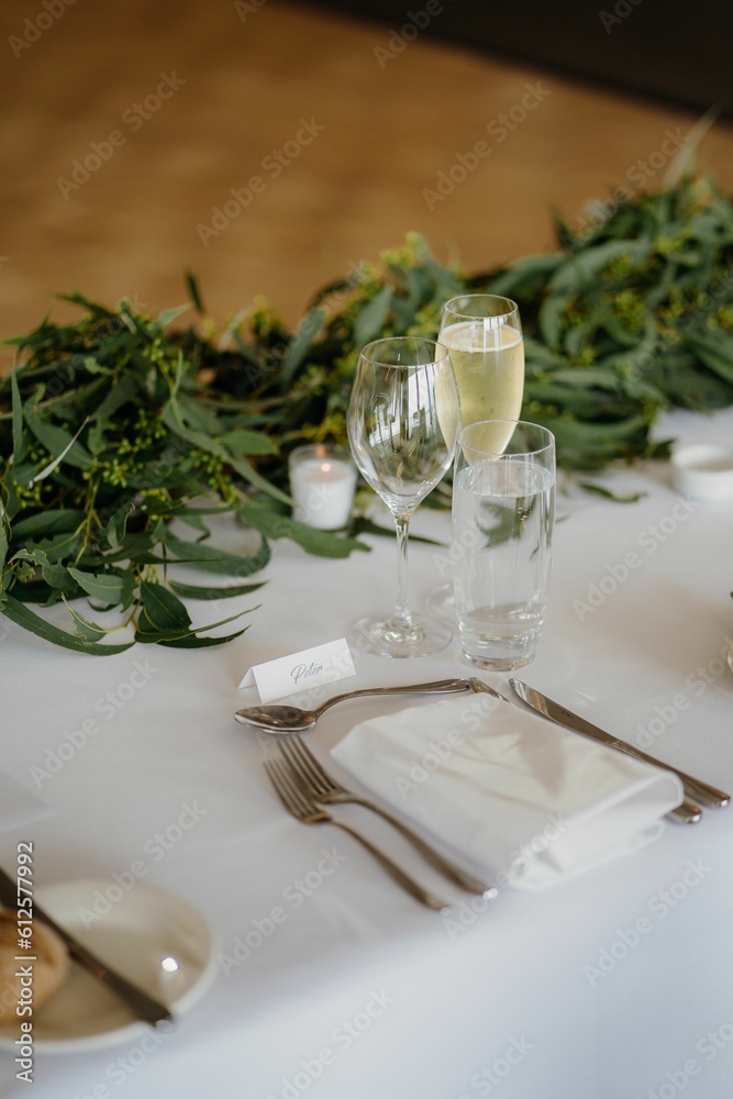 Vertical shot of champagne glasses, napkins and forks on the white table Vertical shot of champagne glasses, napkins and forks on the white table