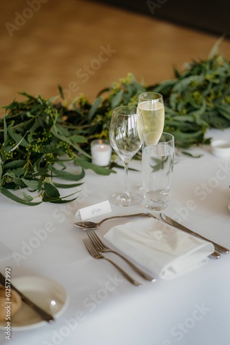 Vertical shot of champagne glasses, napkins and forks on the white table