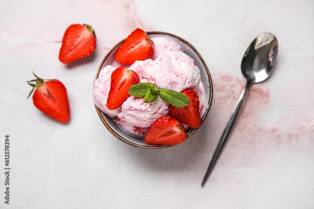 Bowl of strawberry ice cream with berries, mint and spoon on pink table Bowl of strawberry ice cream with berries, mint and spoon on pink table