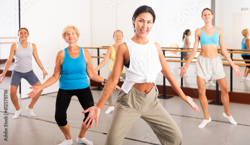 Positive asian woman engaged in dancing in a female group practices energetic swing in a dance studio