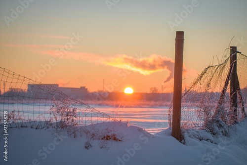 Snowy field with urban silhouette background and sunset over it