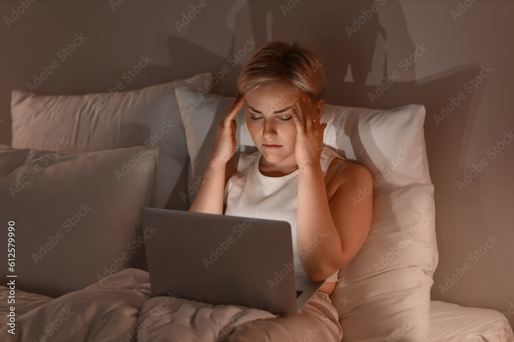Sleepy young woman using laptop in bed at night Sleepy young woman using laptop in bed at night