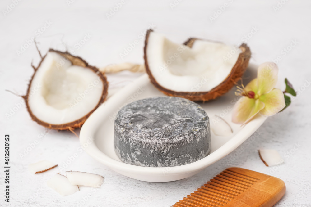 Stand with handmade solid shampoo, coconut, orchid flower and hair comb on light background, closeup Stand with handmade solid shampoo, coconut, orchid flower and hair comb on light background, closeup