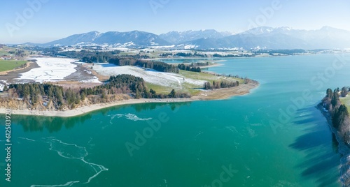 Aerial view of a stunning seascape and snowy coast in Forggensee reservoir, Allgau
