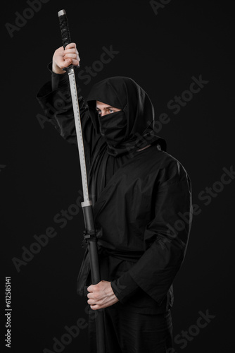 Male ninja with sword on black background