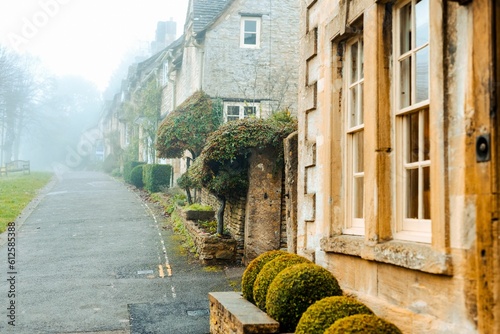 Beautiful shot of old houses along a narrow street on a foggy day in Burford, Cotswolds, Oxfordshire photo