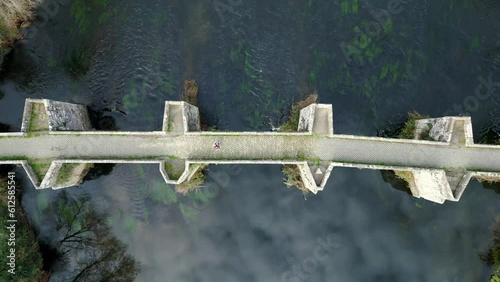 Aerial footage of a person standing on an old bridge with beautiful architeture photo