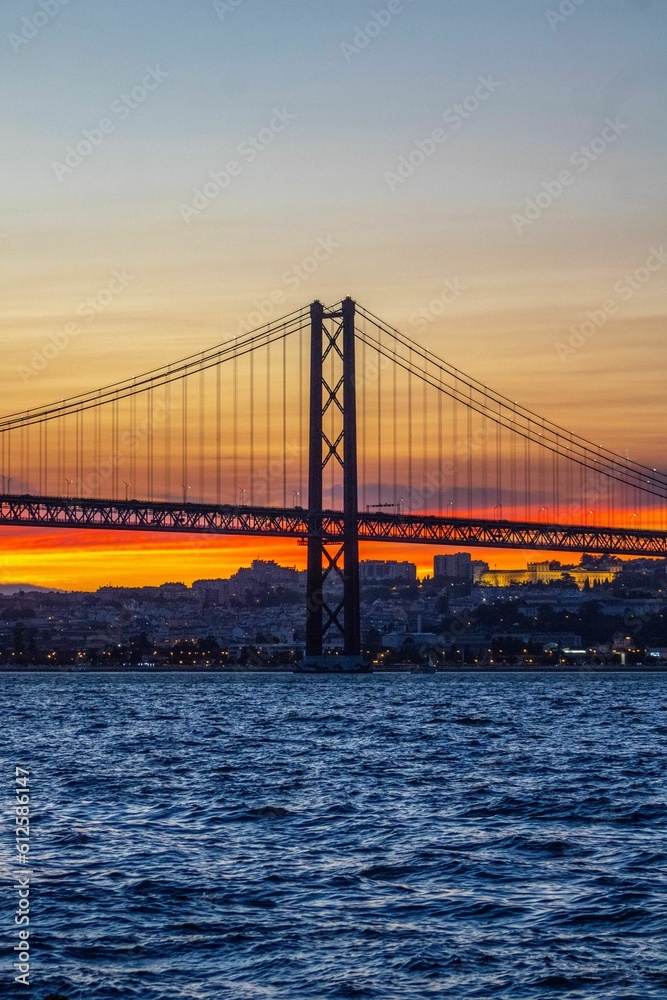 Vertical shot of the The 25 de Abril Bridge at sunset in Lisbon, Portugal.