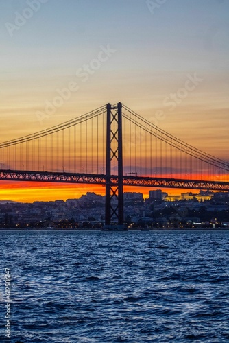 Vertical shot of the The 25 de Abril Bridge at sunset in Lisbon, Portugal.