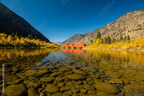 Closeup shot of the clean water and the stones under the Similkameen river with a red bridge. photo