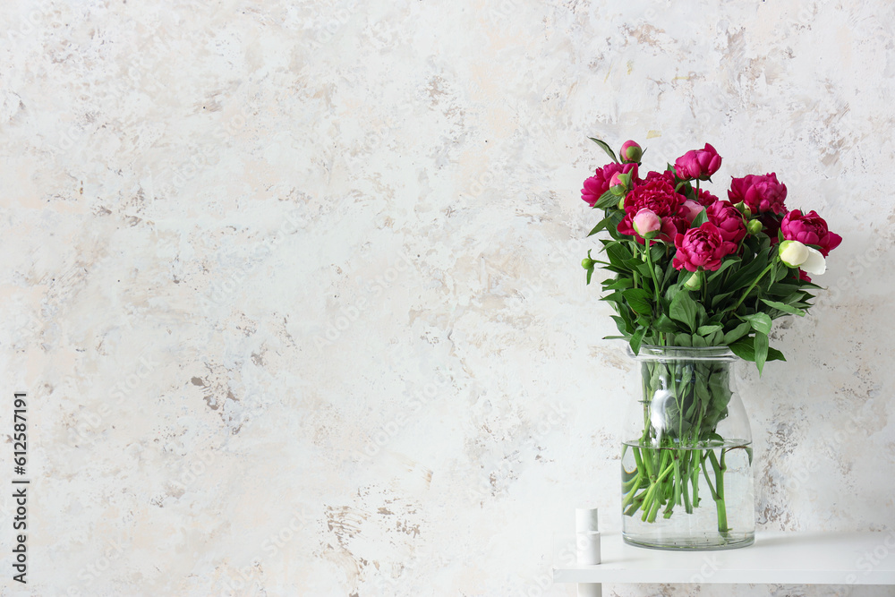 Vase with red peonies near beige grunge wall