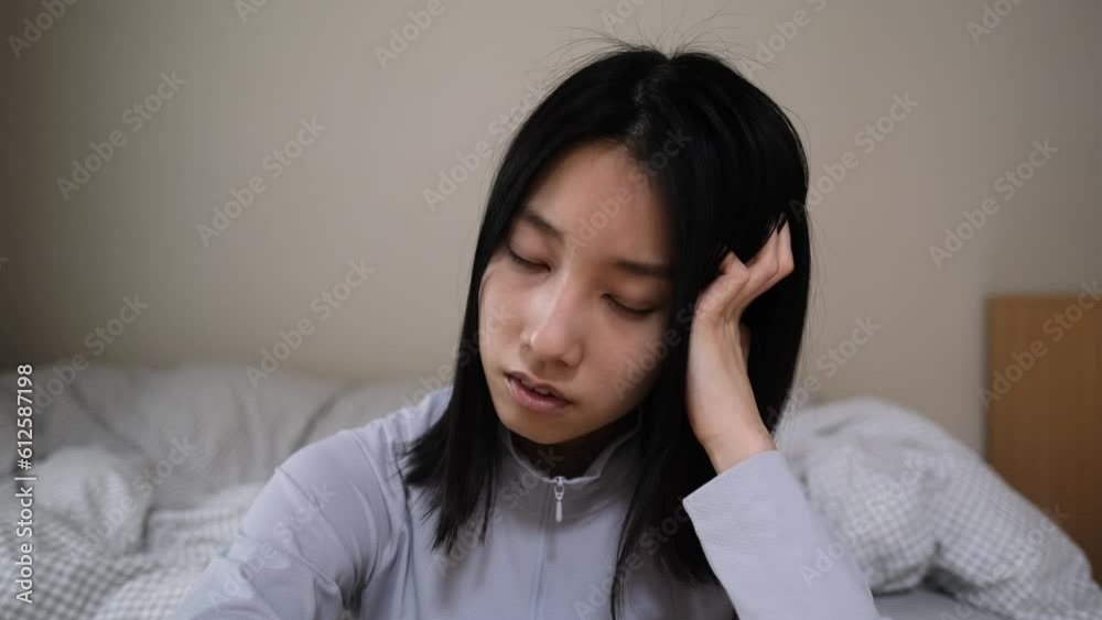 寝室で頭を抱えて悩む若い女性 寝室で頭を抱えて悩む若い女性