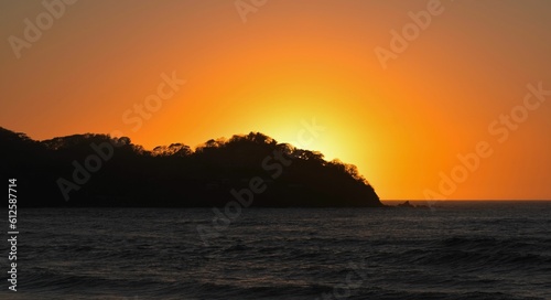 Silhouette of an island against the glowing sun in the sunset sky © Jimena Kim/Wirestock Creators