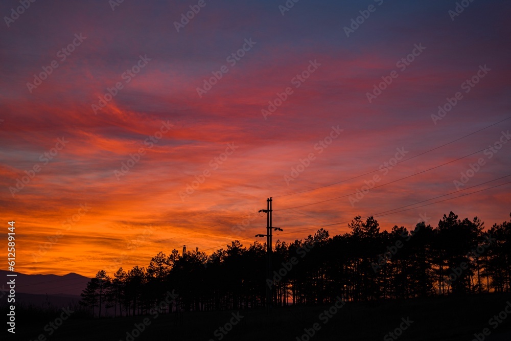 Dramatic sky view at sunset, power lines and stations silhouettes against purple clouds