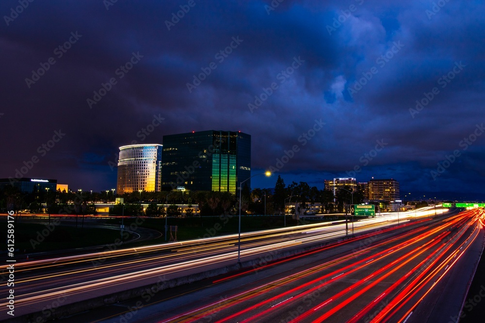 Long exposure of the car lights on the highway of an urban city under the gloomy clouds