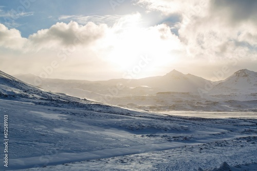 Distant shot of mountains and fields covered with snow under the shining sun © Jos Vanaubel/Wirestock Creators