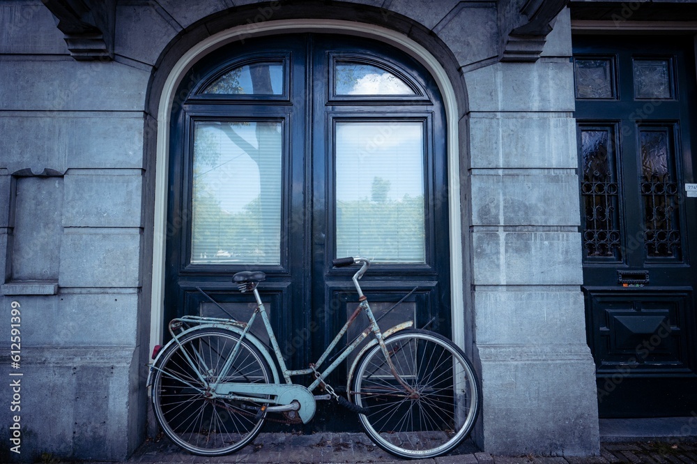Old bicycle parked on the street next to a building in daylight in Amsterdam, the Netherlands
