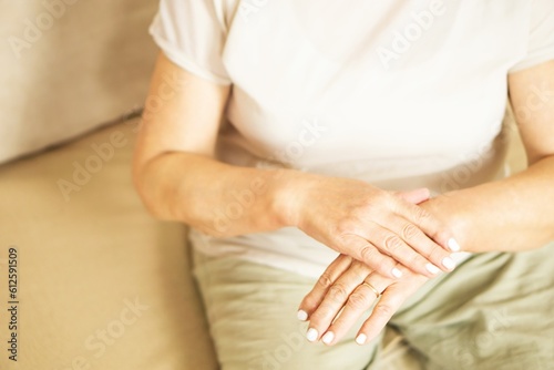Close up of a senior woman appllying hand cosmetic cream at home.