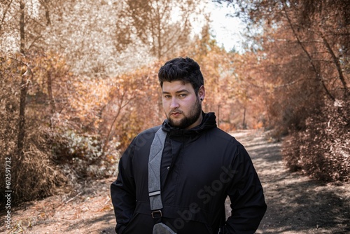 Caucasian man posing and looking at the camera with the autumn forest in the blurred background © Joan Borràs Vinent/Wirestock Creators