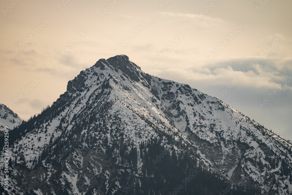 Obraz premium Large mountain covered in snow with a few clouds in the sky