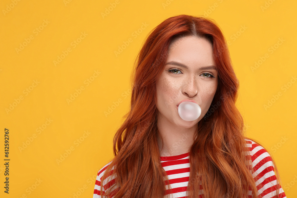 Portrait of beautiful woman blowing bubble gum on orange background. Space for text Portrait of beautiful woman blowing bubble gum on orange background. Space for text
