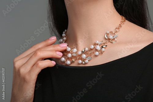 Woman with elegant necklace on dark grey background, closeup