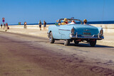 Coche clásico convertible paseando con turistas por el malecón de la habana Cuba un día soleado de verano.