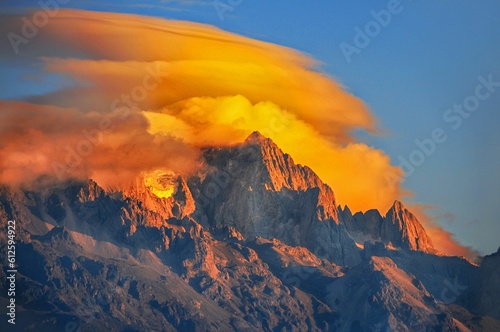 Scenic shot of the peak of a high mount covered with fiery clouds