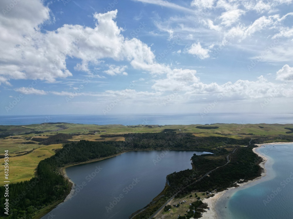 Drone shot of a beautiful green coast land under blue cloudy sky