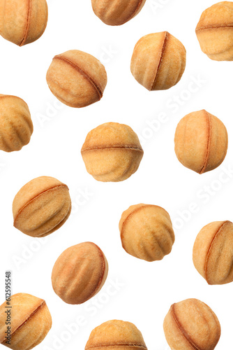 Many delicious nut shaped cookies with caramelized condensed milk falling on white background