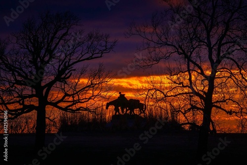 Silhouette of the Pioneer Mother Memorial in downtown Kansas City with an orange sunset sky