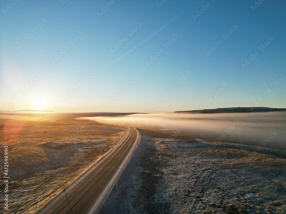 Beautiful view of an empty country road at foggy sunset. Iceland.
