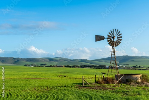 Beautiful view of a farm windmill in a green meadow during sunrise