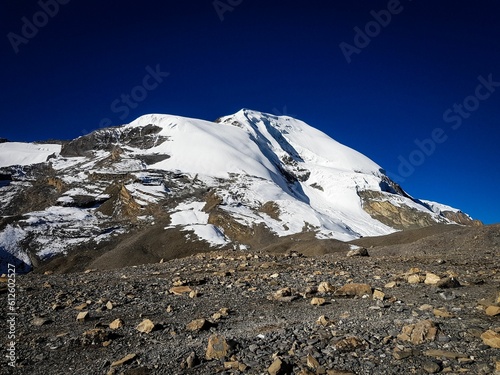 Snow-covered mountain captured from the mountain pass Thorong la pass against the blue cloudless sky photo