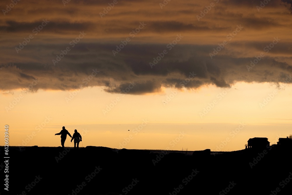 Silhouette of two people having fun walking around under a sunset sky