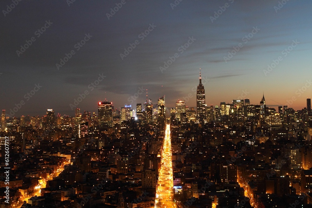 Fototapeta premium Drone view of the cityscape of New York City with many buildings and skyscrapers at night in the USA
