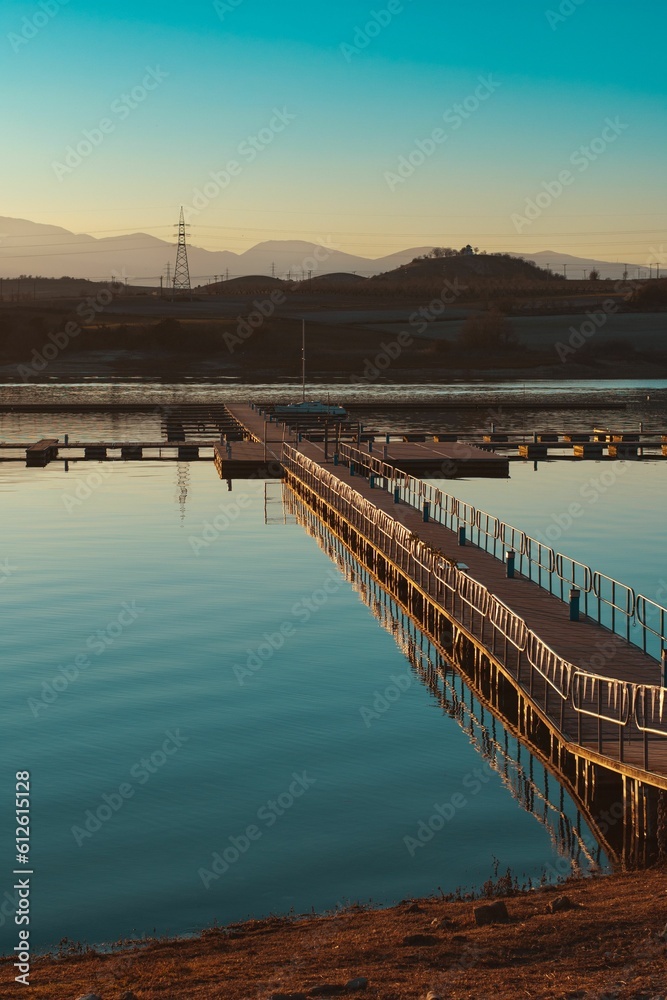 Fototapeta premium Vertical shot of a bridge built on a river against the mountains in the distance