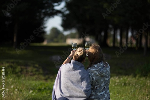 Back view of two women drinking white wine at the park