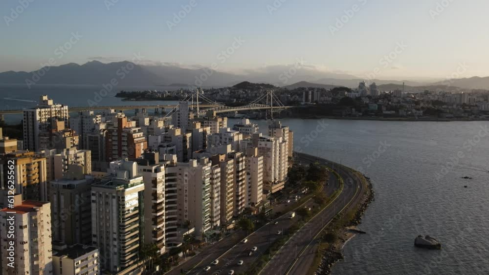Aerial view of a highway filled with cars on the coast of an ocean with buildings on the other side Aerial view of a highway filled with cars on the coast of an ocean with buildings on the other side