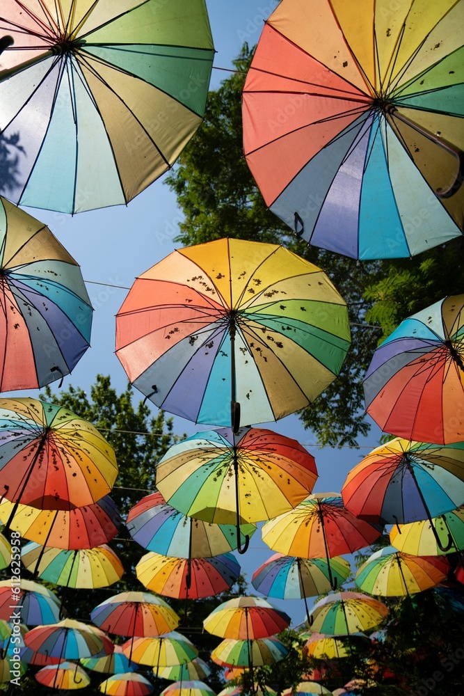 Low angle of colorful umbrellas hanging along street on a sunny day