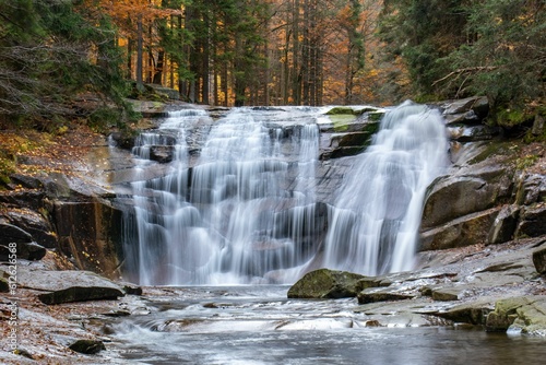 Long exposure shot of the splashing waves o the waterfall in the autumn forest