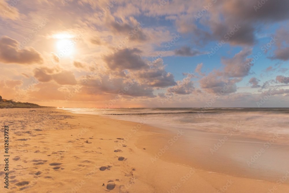 Beautiful shot of a sandy beach under a cloudy sky during a sunset
