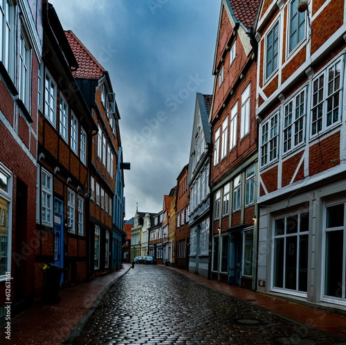 Empty street in a town with brick houses under a gloomy sky © Mikhail Koretskiy/Wirestock Creators