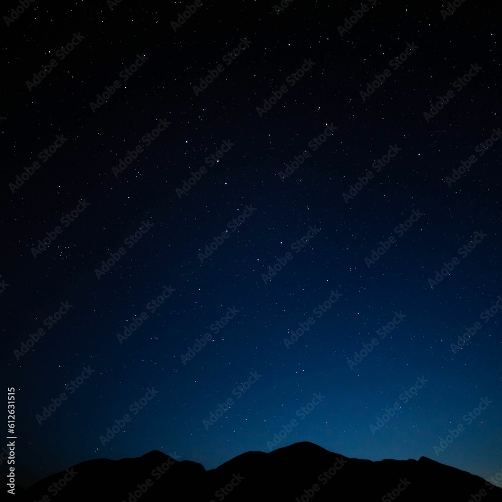 Scenic view of a dark night sky full of stars above a silhouette of a mountain range Scenic view of a dark night sky full of stars above a silhouette of a mountain range