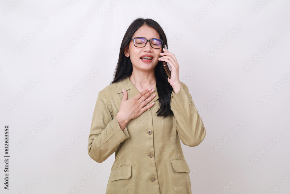 Relieved young civil servant woman getting good news from her phone while holding her chest Relieved young civil servant woman getting good news from her phone while holding her chest