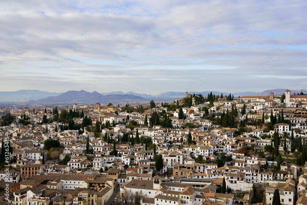 Cityscape with an array of white buildings surrounded by lush mountains in the background