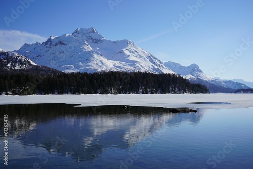 Tranquil winter landscape featuring a serene lake with a dusting of snow