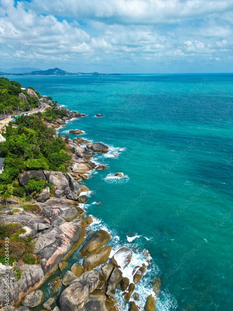 Fototapeta premium Aerial view of an expansive ocean contrasted by the deep blue sky and white billowy clouds